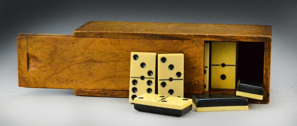 (28) Piece Ivory Domino Set and Wooden Box: Having twenty-eight ivory and ebony wood dominos, in its original slide lid wood box, dominos measure 2" L x 1" W, overall 7.75" L circa early 20th century. Condition: Minor chips to two corners of bo