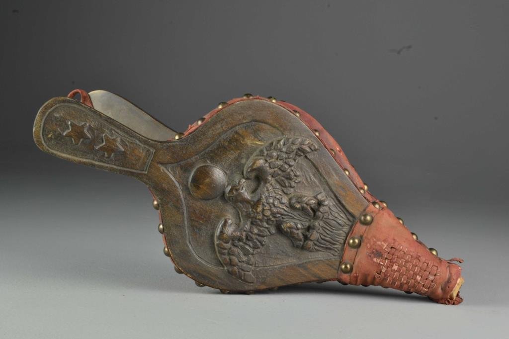 An Antique Carved Wood and Leather Bellows: Finely carved to depict an eagle at center with stars on handle, having brass tacked leather sides with leather threaded cross design to tip, measures 16"L, circa 19th century. Condition: having wear