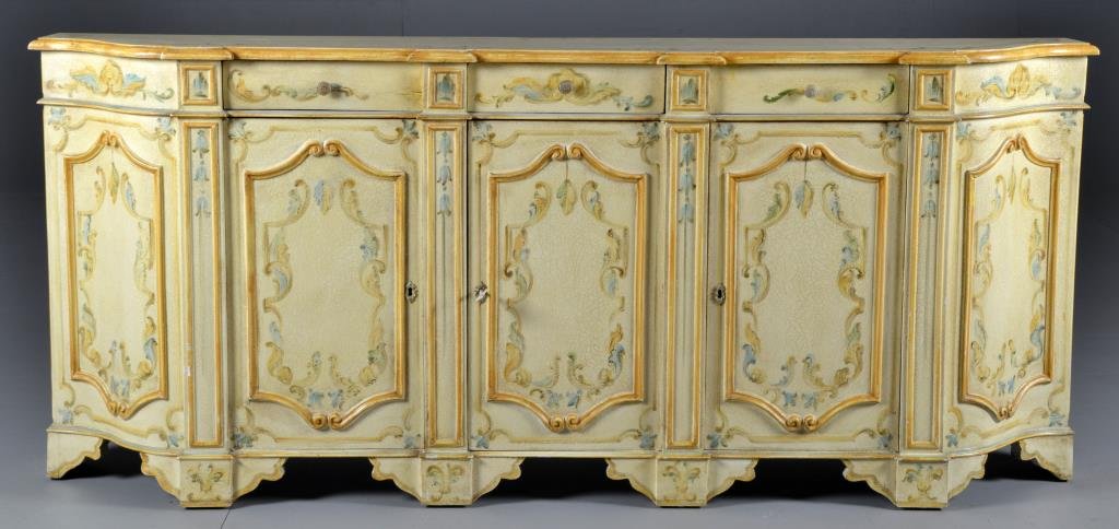 Italian Polychrome Painted Credenza: Having three drawers over three doors opening to a shelved interior, painted in floral and scroll decoration against a crème ground, 75"L X 32.5"H X 13.25"D, circa 20th century.
