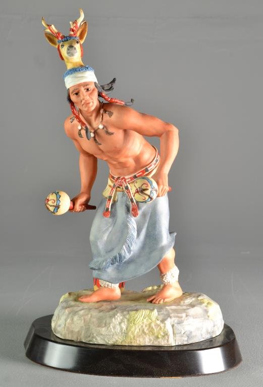 A Cybis Porcelain Native American Figure: Polychrome decorated male figure in ceremonial dress with drum and other instruments, mounted on a metal base, signed "Cybis USA", measures 19"H, circa 20th century.