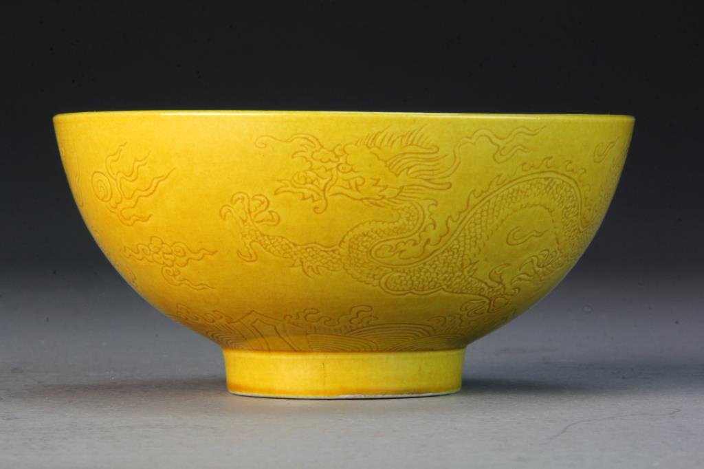 Chinese Egg Yolk Yellow Porcelain Bowl: Finely incised to depict dragons among ruyi clouds, raised on short foot ring, base bearing six character mark within two concentric circles in underglaze black, 2.25"H X 5"D.