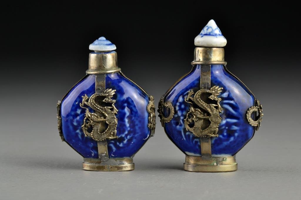 (2) Chinese Porcelain Snuff Bottles: Having metal encasements with depictions of four clawed dragons, beast heads and soldiers on horseback, bases stamped with two character mark and one with additional seal, tallest is 3"H.