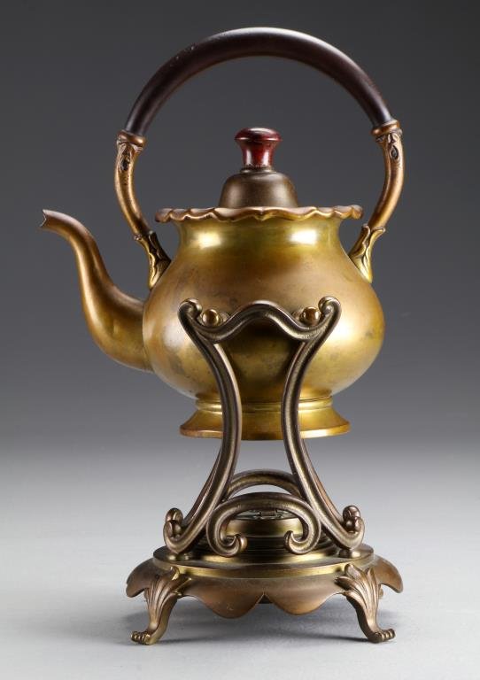 A Queen Anne Style Brass Tea Kettle on Stand: Stamped S & Co. trademark having an ebony wood handle, cabriole legs with valanced skirt, pat. 1895 on the stand, 13"H.