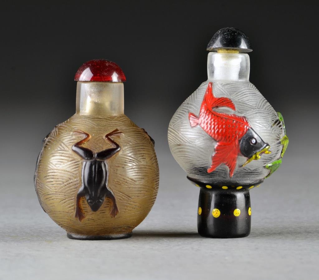 (2) Chinese Peking Glass Snuff Bottles: Two clear glass examples each having incised waved design to background, one with overlay depicting frogs, the other with painted overlay depicting koi fish and having a tall foot, tallest is 2.8"H.