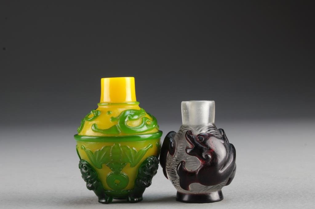 (2) Chinese Peking Glass Snuff Bottles: Two small round examples having overlay in high relief, one depicting mythical serpent that wraps around bottle, the other depicting bats with coins and having three beast head feet, tallest is 2.2"H.