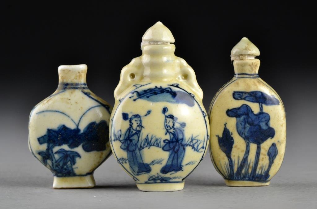 (3) Chinese Blue and Celadon Porcelain Snuff Bottles: One formed as a moonflask painted with depiction of figures within a landscape at center, another depicting cricket and bunches of grapes, together with an example depicting lotus flowers, all with bo