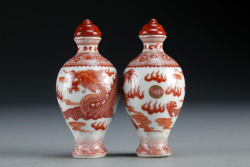 (2) Chinese Iron Red Porcelain Snuff Bottles: Pair of snuff bottles painted to depict five clawed dragon chasing flaming pearl among ruyi clouds, bases bearing four character mark in underglaze iron red, both measure 3.3"H.
