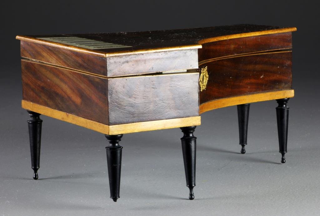 19th C. Piano Form Mahogany Sewing Box: Formed as a miniature piano, with figured mahogany, inlaid ivory and dark wood keyboard at one end, a gilt metals escutcheon to side, four tapered legs, opens to compartmented interior, lid of box wit