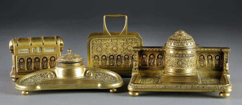 An Ornate German Brass Desk Set: Comprised of two inkwell and pen trays, a letter holder and a calendar, all with ornate scrolling gilt decoration, undersides stamped Germany, largest measures 5"H, circa late 19th-early 20th century,