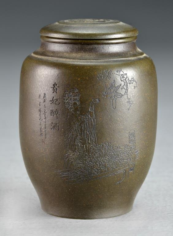 A Chinese Zisha Covered Pot: Molded of simple form, body incised with depiction of a beauty in a landscape scene, having calligraphy to front and reverse, base stamped with seal, measures 4.25"H. Good condition.