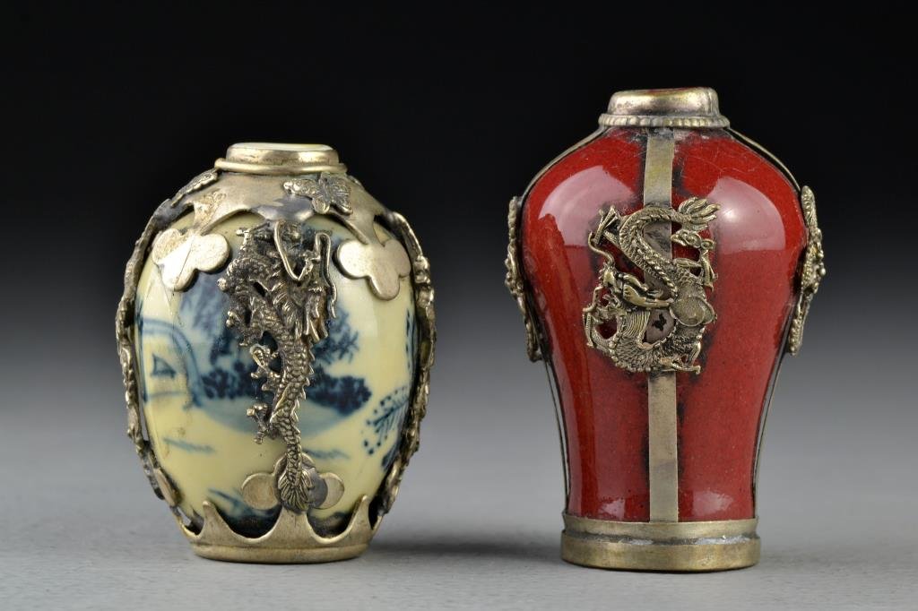 (2) Chinese Porcelain Snuff Bottles: Two porcelain examples with metal encasements depicting butterflies, beast heads, phoenix and dragons, one base stamped with a seal, the other stamped with two character mark, tallest is 2.75"H.
