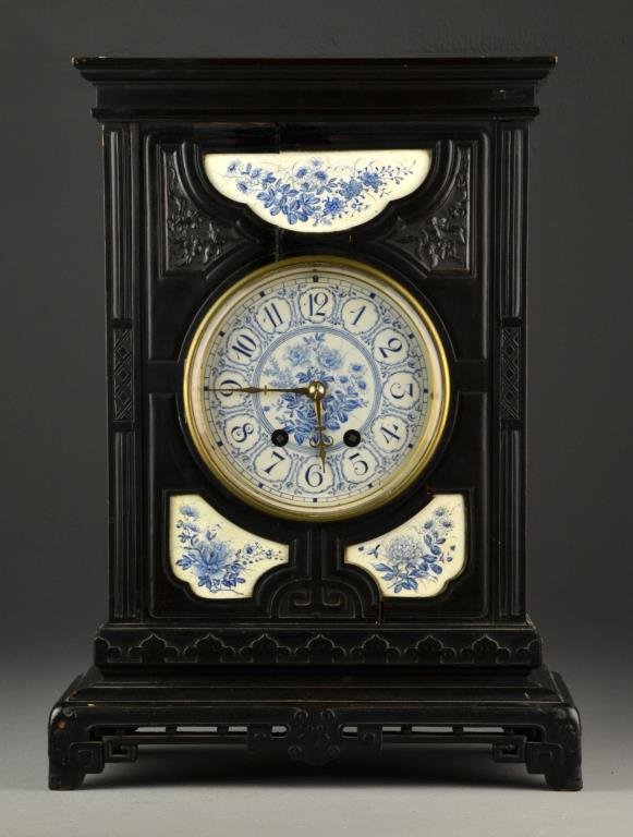 A Delft Ebonized Wood and Porcelain Shelf Clock: Carved in the Chinese Chippendale taste, having Arabic numerals and blue and white porcelain face and panels decorated with floral motif, 8 day strike, measures 17.6"H, circa late 19th-early 20th cent