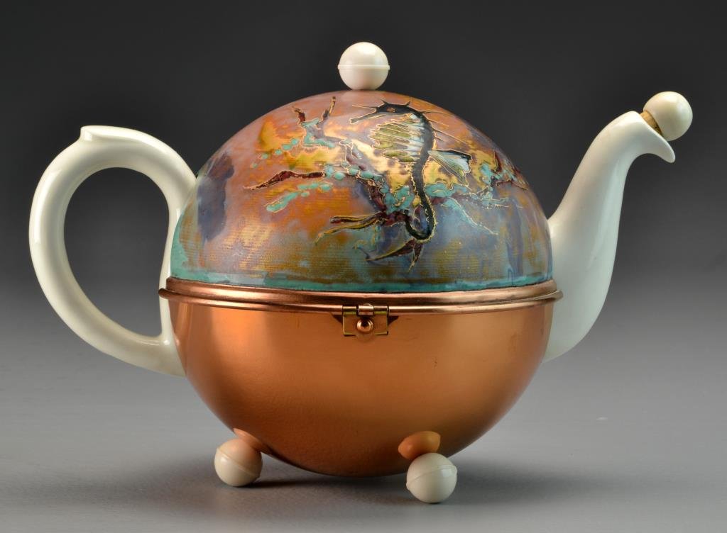 P. Regout & Co. Teapot with Enameled Warmer: A porcelain teapot with sphinx hallmark for P. Regout & Co. Maastricht to underside, further stamped Made in Holland, cased in a copper or brass warmed with enameled decoration to lid depicting seahor