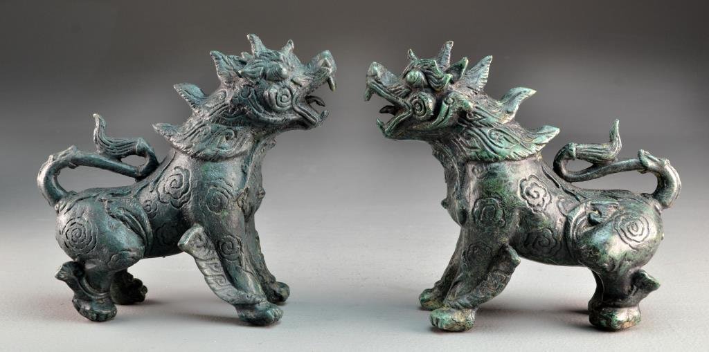 Pr. Chinese Cast Brass Models Of Foo Lions: Having a deep green patina, both standing in the crouched position, 8.5"L, circa 20th century. From the collection of the late Anthony "Tony" Orlando Dearborn Heights, Michigan. Anthony Orlando began