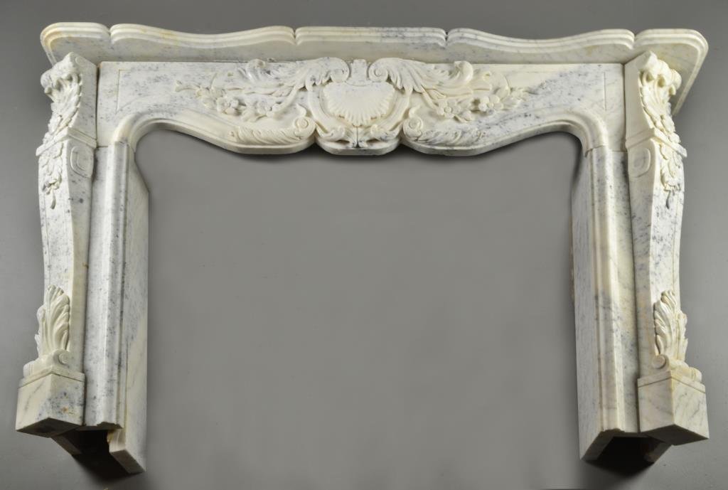 French Louis XV Style Carved Marble Mantle: A mantle surround having a shaped top above a central carved shell motif, having scroll, acanthus leaf and floral decoration, four pieces, measures approximately x 68"W, circa 20th century.