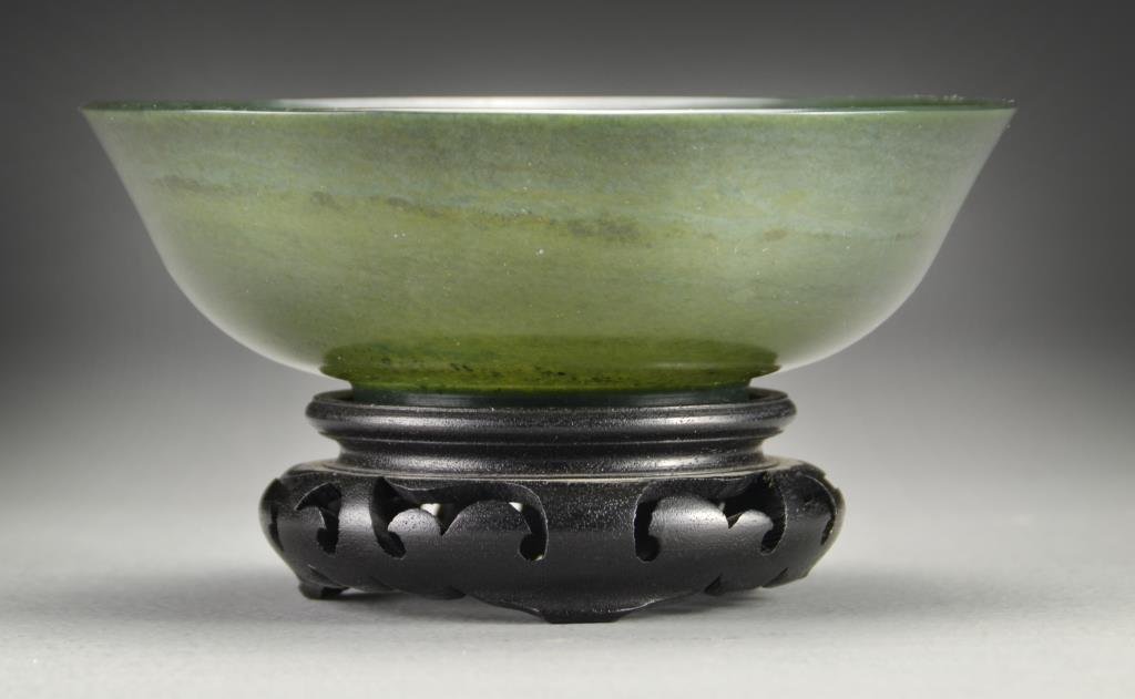 A Fine Chinese Carved Jade Bowl: Meticulously carved of a dark green spinach jade, having slightly flared rim and raised on short foot ring, exhibiting fine polish, the stone an all over even green with specks of gold colored inclusi
