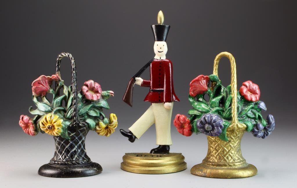 (3) Cast Iron Doorstops: To include two cast iron flower basket examples, antique to semi-antique, together with a soldier modeled metal doorstop, largest measures 13"H. Property of a Birmingham Michigan Family.