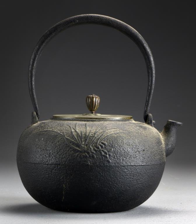 Japanese Meiji Cast Iron Teapot: Having molded tall grass decoration to one side and calligraphy to the reverse, the appears to be copper with an artist signature to the interior, 8.5"H including handle, circa Meiji Period. Property 