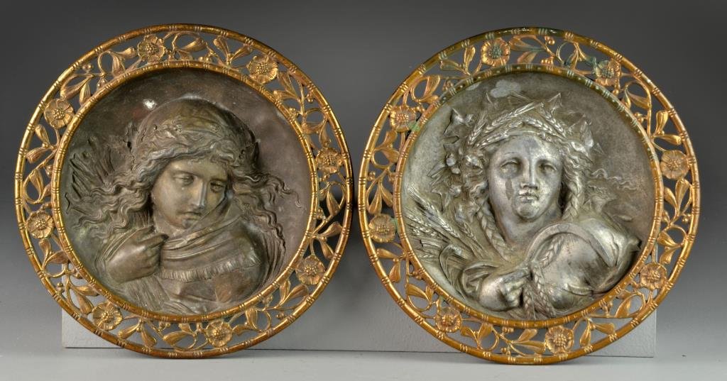 Pr. Antique Figural Metal Hangings: Each depicting the bust of a woman, one holding wheat and a sickle, the other holding a bundle of wood, possibly lead with gilt pierced floral borders, measure 11.25"Dia., circa late 19th-early 20th c