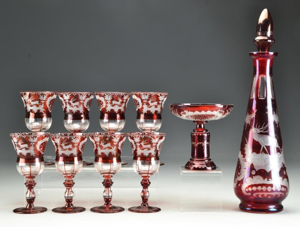 (10) Pc Antique Cranberry Cut to Clear Decanter Set: Having a decanter with rounded stopper, eight cordials and a footed compote, cut to depict landscapes with elk and geese, decanter measures 15"H, circa late 19th-early 20th century. Property of a Birm