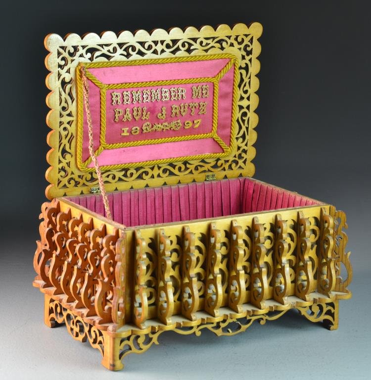 A Folk Art Wooden Memento Box, Dated 19th C.: Raised on four legs, carved all over with scrolling motif, the stepped lid and bottom ridge having a scalloped edge, lid with central depiction of a dove, opens to a red satin lined interior with gold