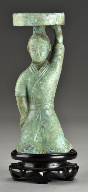 A Chinese Shang-Zhou Style Bronze Figural Oil Lamp: Depicting a figure kneeling holding the basin above his head, wearing long flowing robes and having finely detailed facial features, raised on a hardwood stand, 8.25"H not including stand, circa 18th-