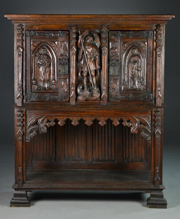Gothic Revival Carved Wood Cabinet: Carved at center to depict Michael slaying the serpent Satan, the two cabinet doors carved with religious figures holding sword and key, fitted with metal figural locks, raised above a carved floral a