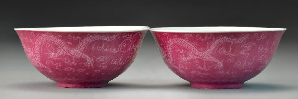 Pr. Chinese Raspberry Glaze Porcelain Bowls: Depicting dragons chasing a flaming pearl against a pink ground, having slightly flared rim and raised on short foot ring, base having four character mark in iron red, 2"H X 4.5"D, circa early to mid-