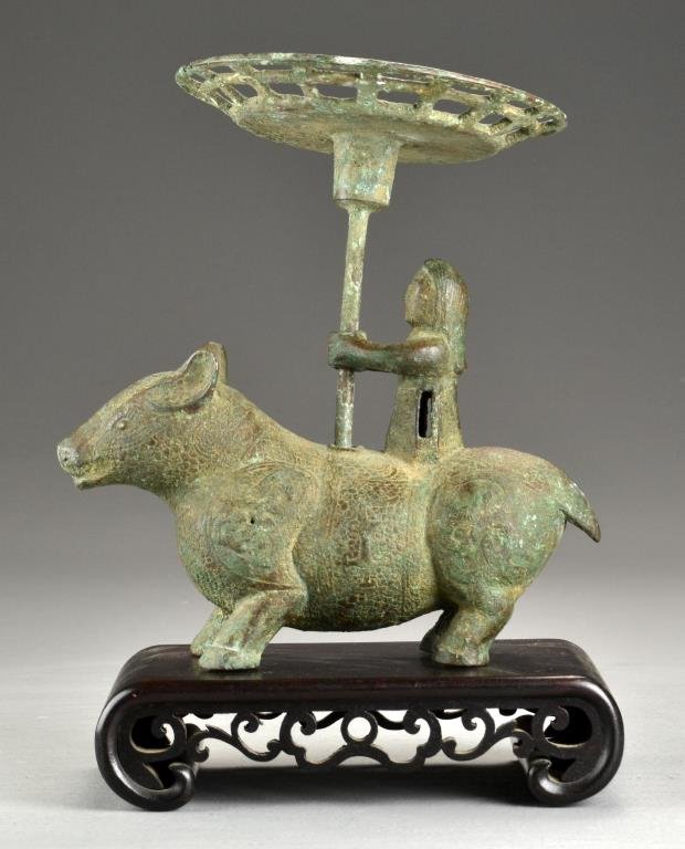 A Fine Chinese Zhou Style Bronze Figure on Mythic: Depicting a rider holding a shallow dish extended atop a removable pole riding on a mythical beast decorated with symbols, now raised atop a hardwood stand, 8.5"H without stand., circa 19th century an