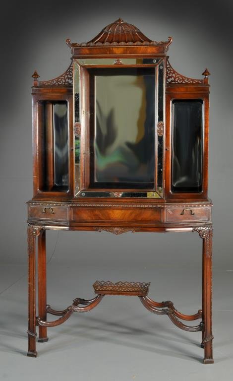 Chinese Chippendale Style Cabinet: Having a heavily carved and pierced cornice with upright finials, above three glazed doors, all opening to reveal glass shelves and with mirrored backs, below having one large shaped drawer raised on 