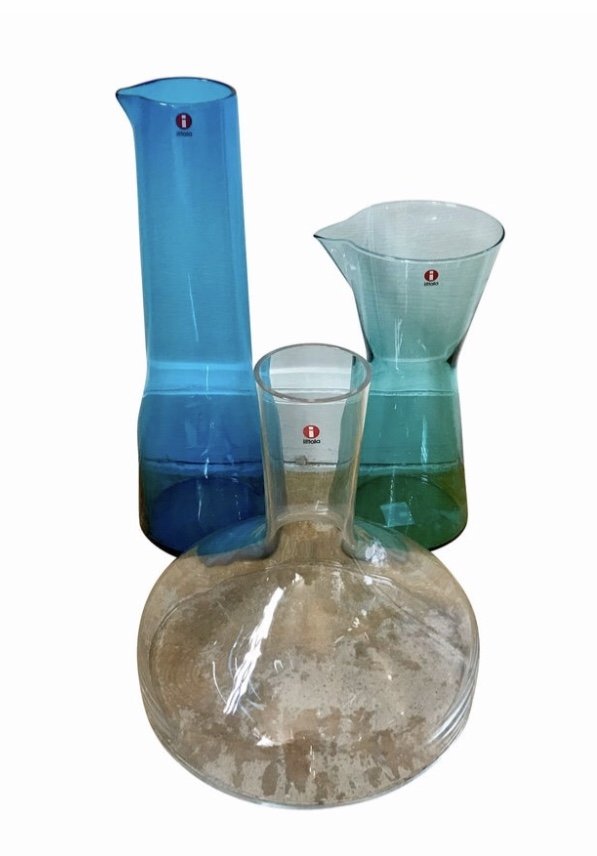 Three Mid Century Modern Iittala Decanters by Kaj Frank: Set of three Iittala Finland decanters in like new unused condition. Consisting of one wine decanter and two beverage vessels. Iconic design by Kaj Franck, Finland.
