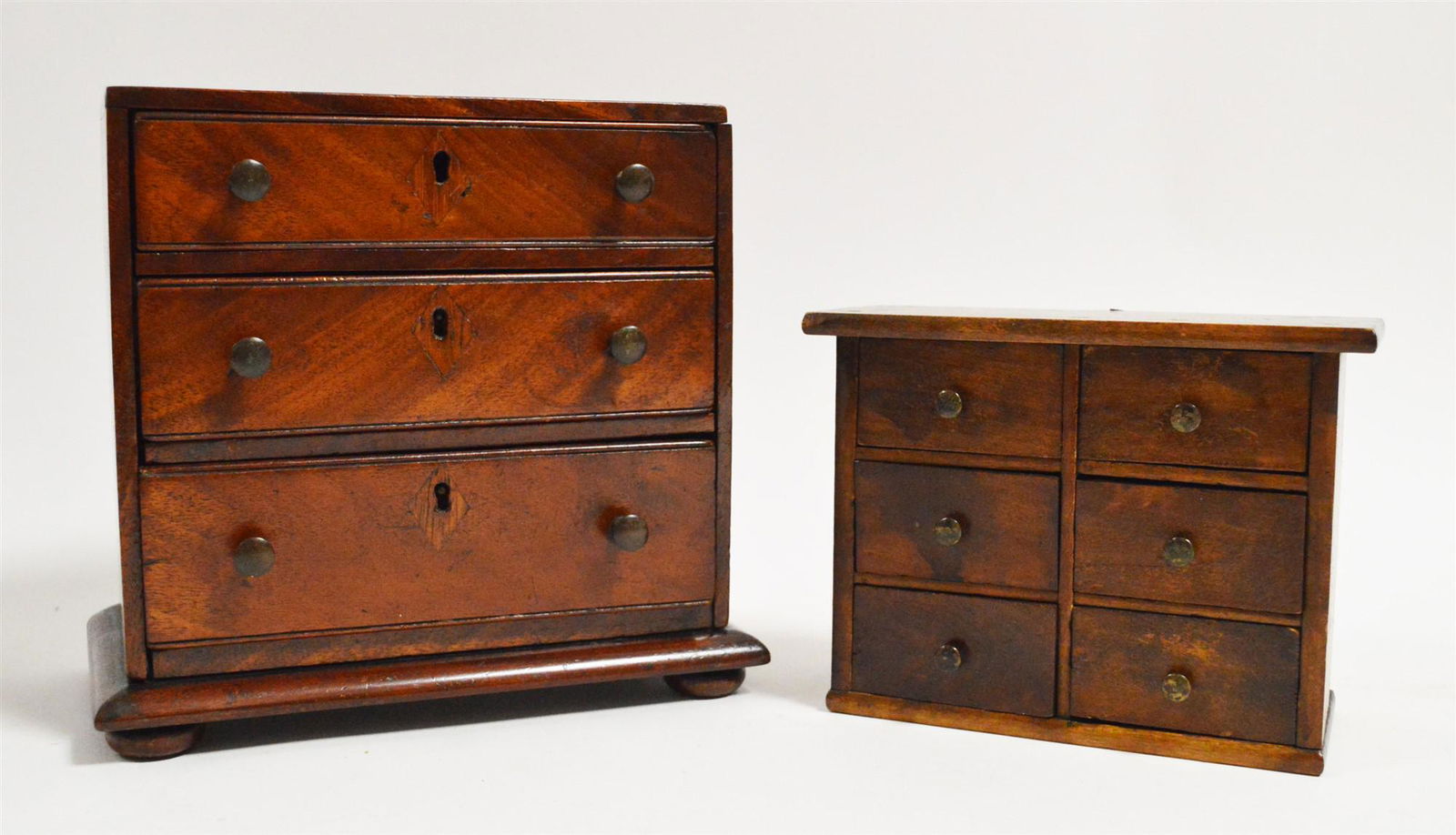 Two miniature chest of drawers: An early 19th Century miniature mahogany chest of drawers, the three graduated drawers with brass handles, 23 x 13 x 20cms high; and a later chest of six drawers. Sale Section/Category: Miniature furn