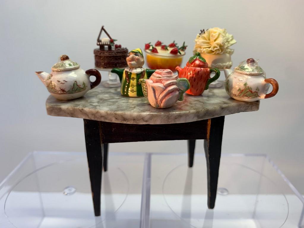 8 Piece Lot Artisan Made Cakes & Teapots: This lot has two beautiful cakes by Lesley Burgess of The English Kitchen. The chocolate cake with a tiny piano is offered as well as a fancy white cake on a glass cake stand. The teapots are all diff