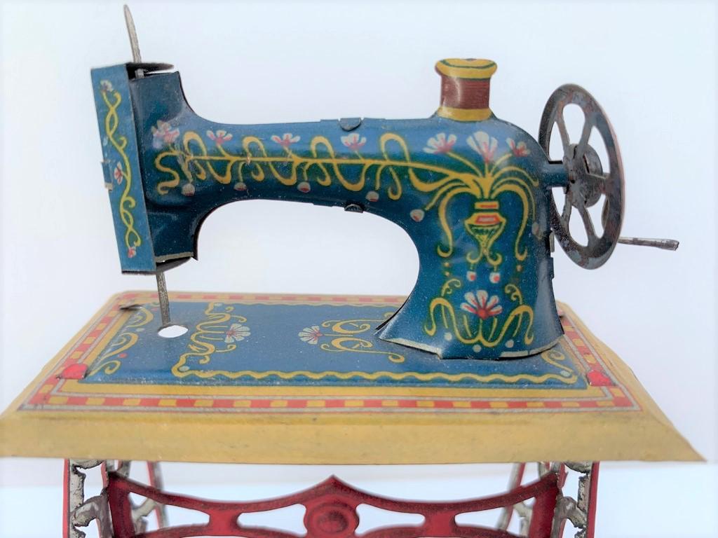 German Lithographed Antique Tin Sewing Machine: Blue in color, this lithographed sewing machine is from Germany. Red base. Early 1900's.