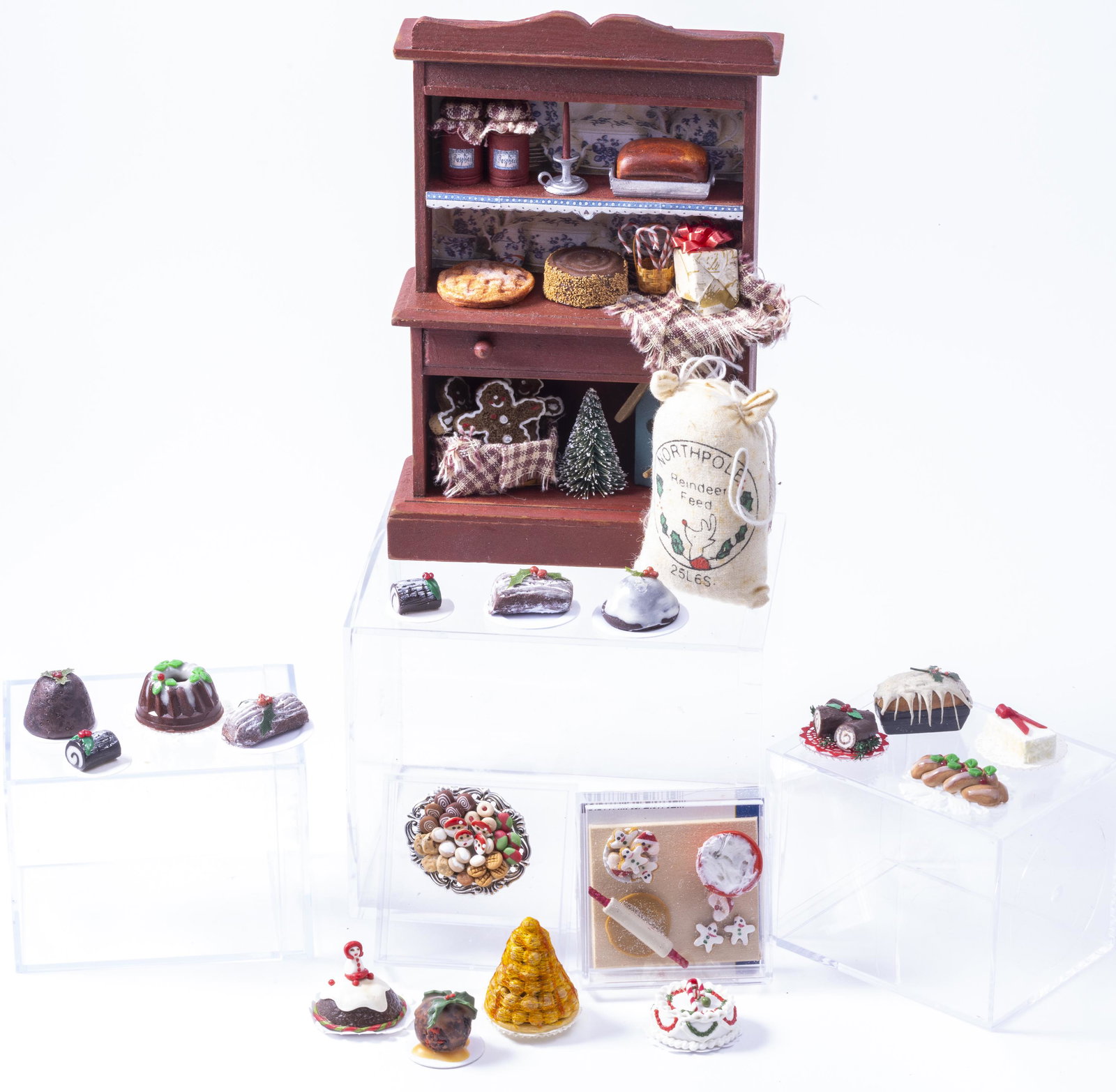 Decorated Christmas Cabinet with Christmas Foods & More: Decorated Christmas cabinet filled with Christmas treats. There are additional Christmas cakes as well including plum pudding, yule log and a Bundt cake. The bottom right hutch has a piece of wood mis