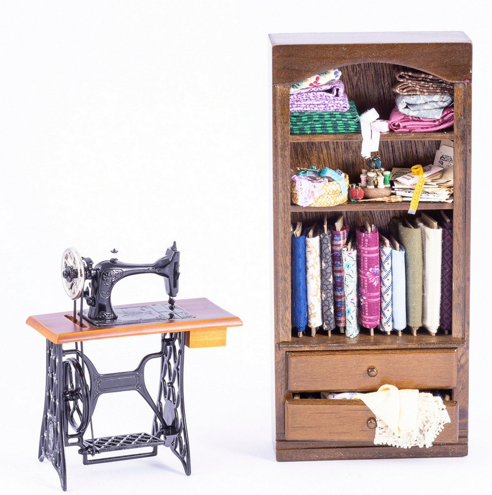 German Sewing Machine with Decorated Sewing Cabinet: German sewing machine with a wooden handmade decorated sewing cabinet. There's bolts of fabric and sewing notions in the cabinet.