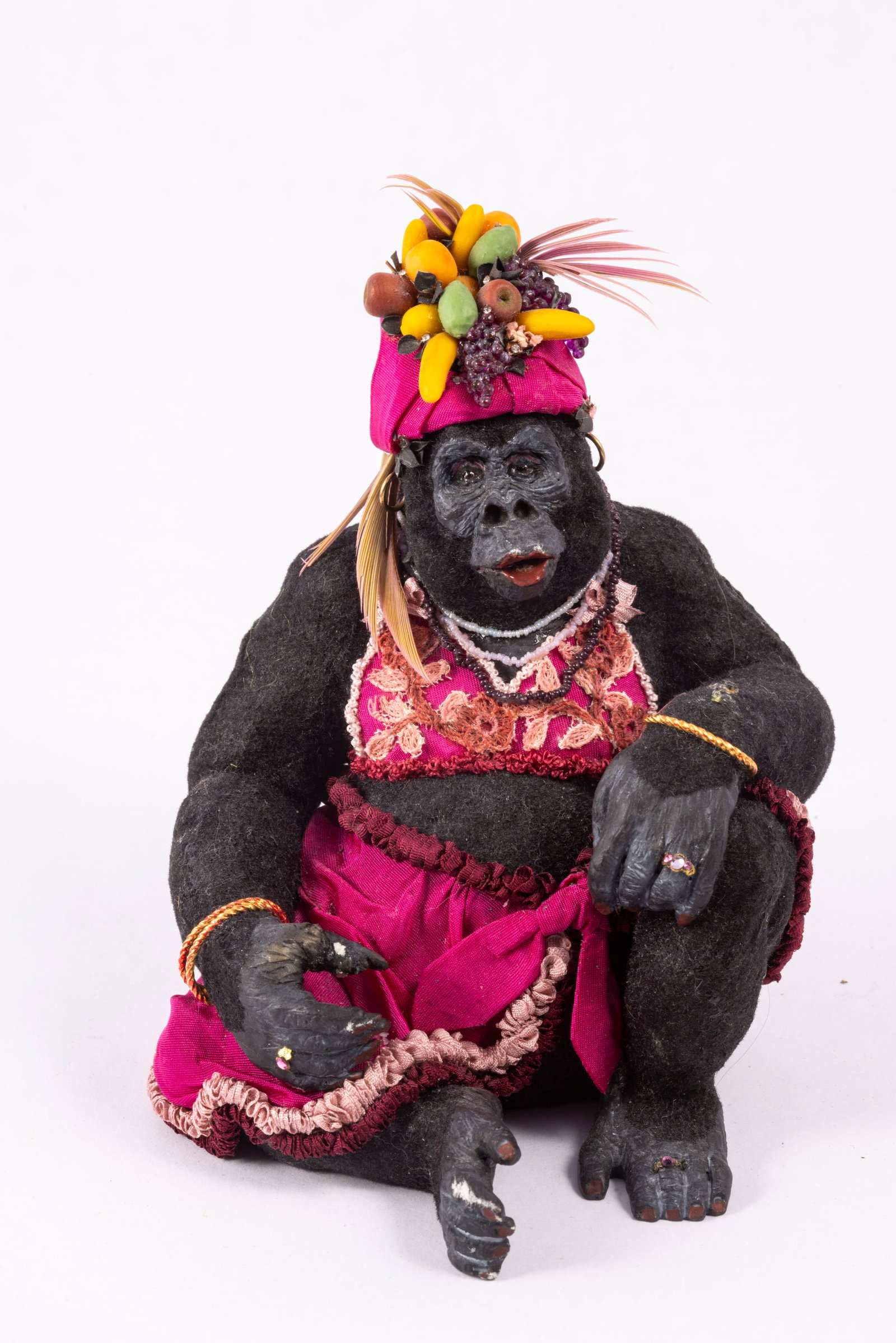 Todd Krueger Female Gorilla In Fruit Hat: Todd Krueger female gorilla in dark pink skirt and top, as well as a matching hat with fruit. There is a mark of white on her hand and foot which may have originally had something there, so please not