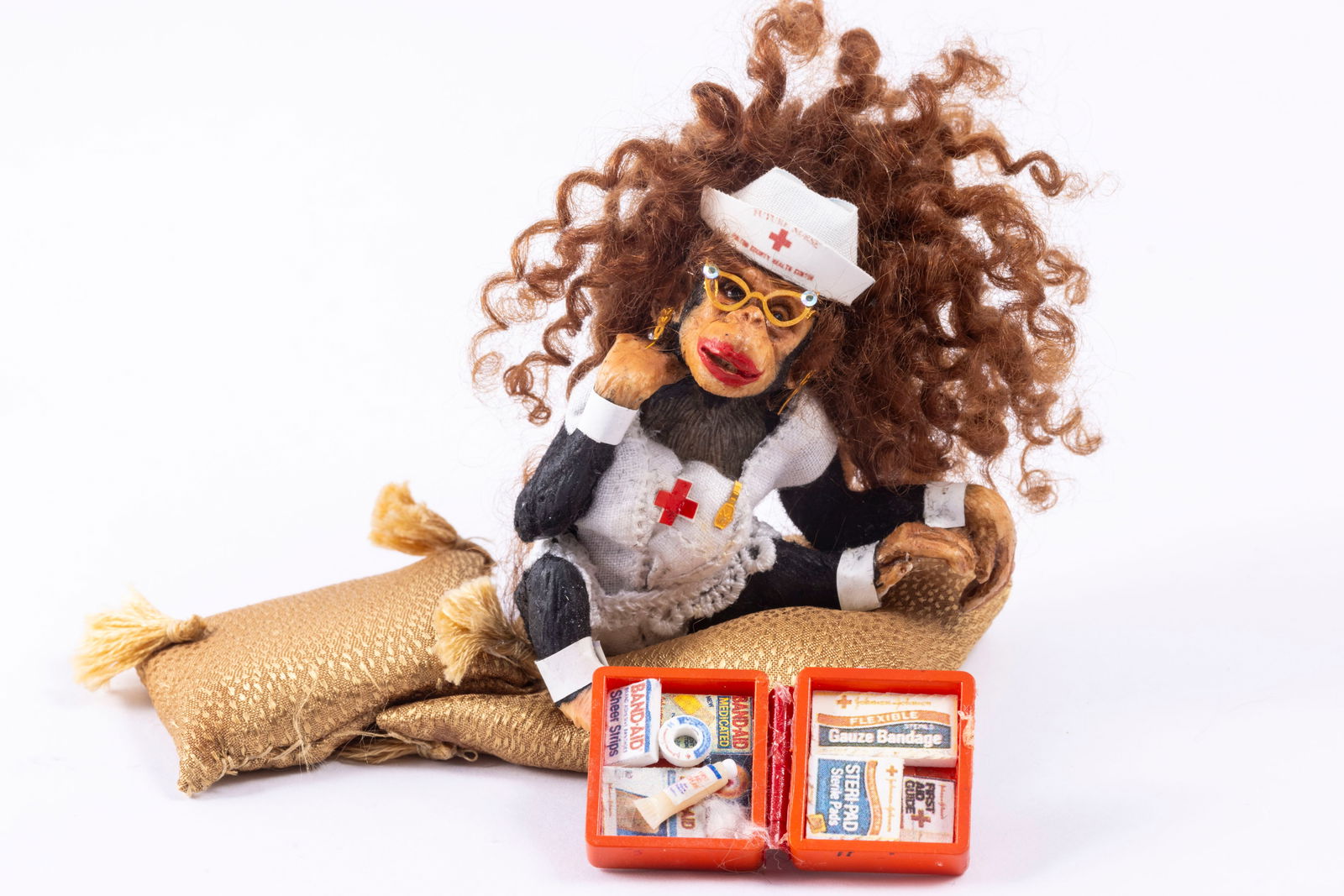 Todd Krueger Chimpanzee Nurse: Todd Krueger Chimpanzee nurse with a medical kit. She's sitting and her hands and feet do have some chipped damage, please note. She has big curly hair, and comes with two gold pillows with tassels.