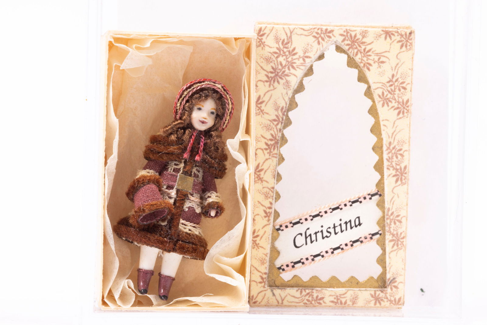 Renee Delaney Christina Doll in Box: So tiny, by Renee Delaney. The box with the Christina doll. She's wearing a burgundy dress and hat.