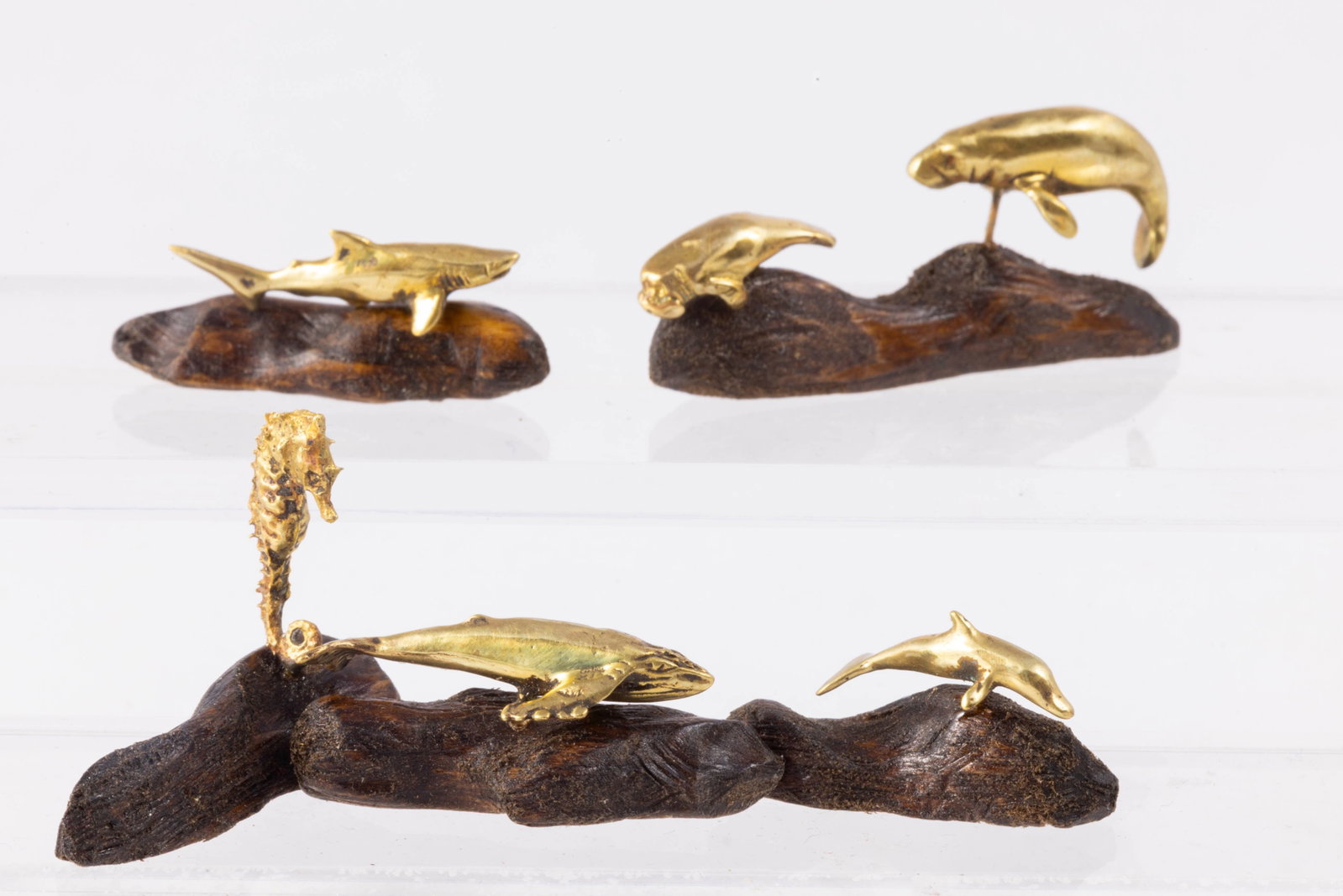 Ron Stetkewicz Brass Sea Life on Wooden Base: Different sea life on wooden bases. There's a walrus and baby walrus, a shark, a sea horse, dolphin and fish. IGMA artist Ron Stetkewicz.