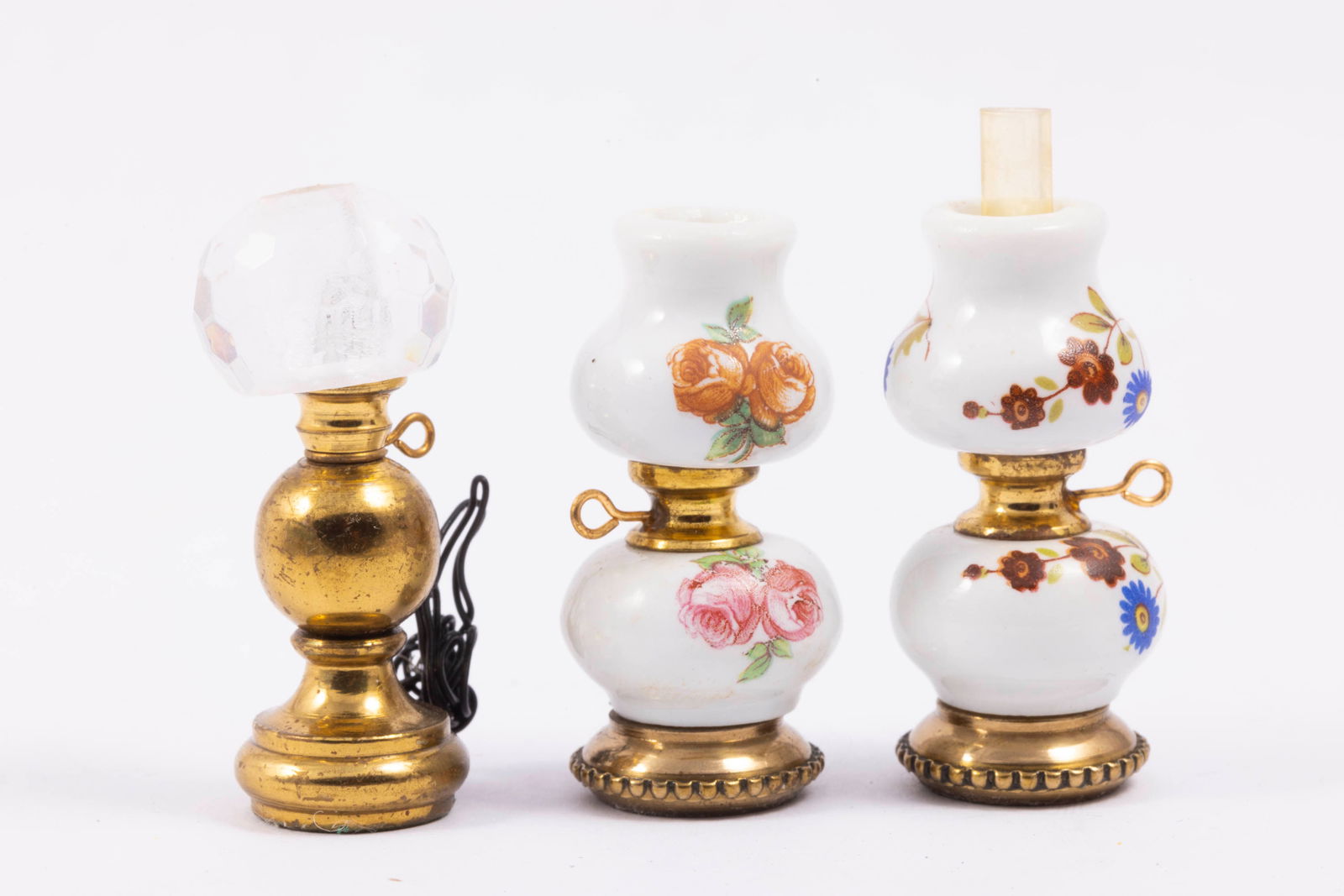 Vintage Oil Lamps with 2 Porcelain Lamps: Two porcelain oil lamps with floral d?cor. The porcelain lamp has a glass hurricane, but the other one is missing. The other oil lamp is gold colored with a clear top.