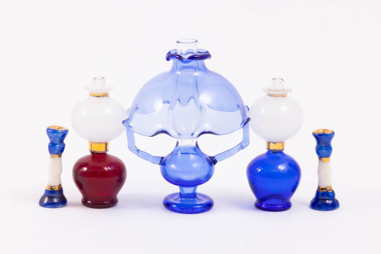 Handmade Glass Lamps with Porcelain Candlesticks: There are three beautiful glass lamps in the auction. The large blue glass lamp in the center, as well as the smaller and just as beautiful red and blue oil lamps. The pair of blue and white candlesti