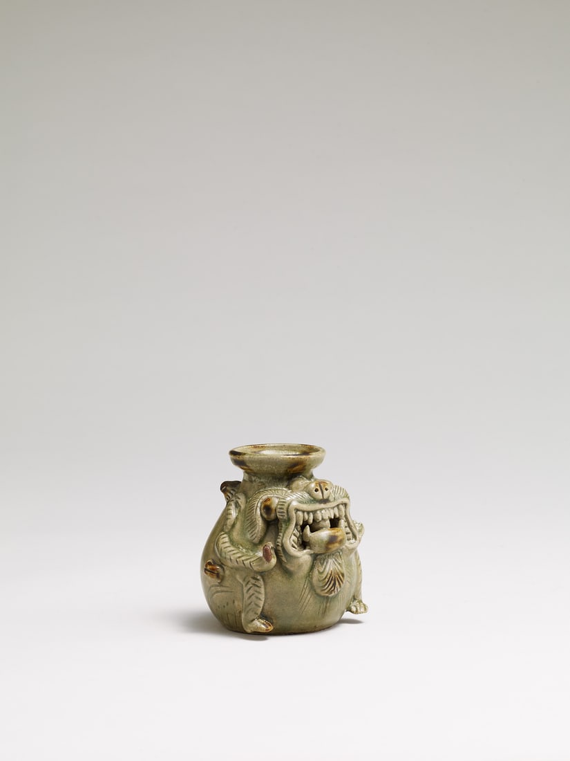 A CELADON-GLAZED FIGURE OF A MYTHICAL BEAST: 品名(title):西晉 青瓷神獸。年代(Age): WESTERN JIN DYNASTY(266-316 A.D.)。 尺寸:8.4 cm Height。 來源