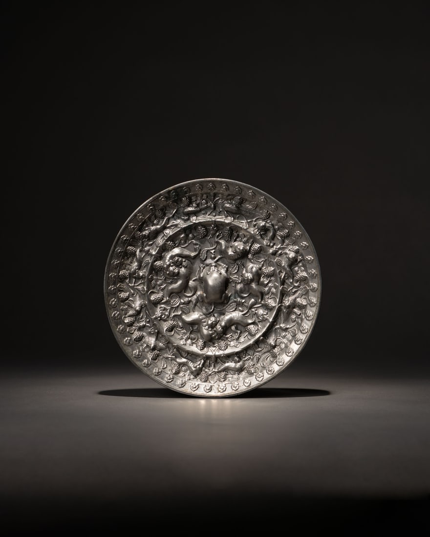 A BRONZE 'GRAPES AND BEASTS' MIRROR: 品名(title):唐 青銅海獸葡萄鏡。年代(Age): TANG (618-907 A.D.)。 尺寸:16.6 cm Diameter。