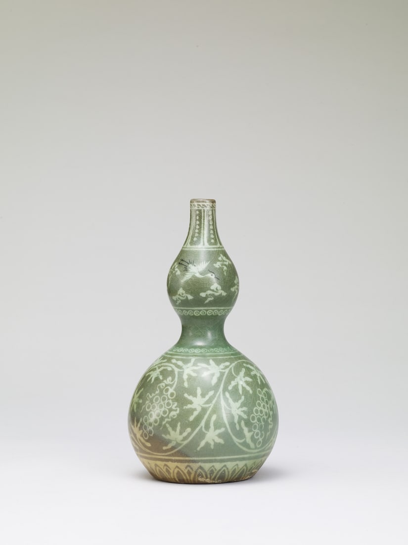A CELADON-GLAZED DOUBLE-GOURD VASE: 品名(title):高麗 青瓷象嵌葫蘆瓶。年代(Age): GORYEO DYNASTY (918-1392 A.D.)。 尺寸:22 cm Height