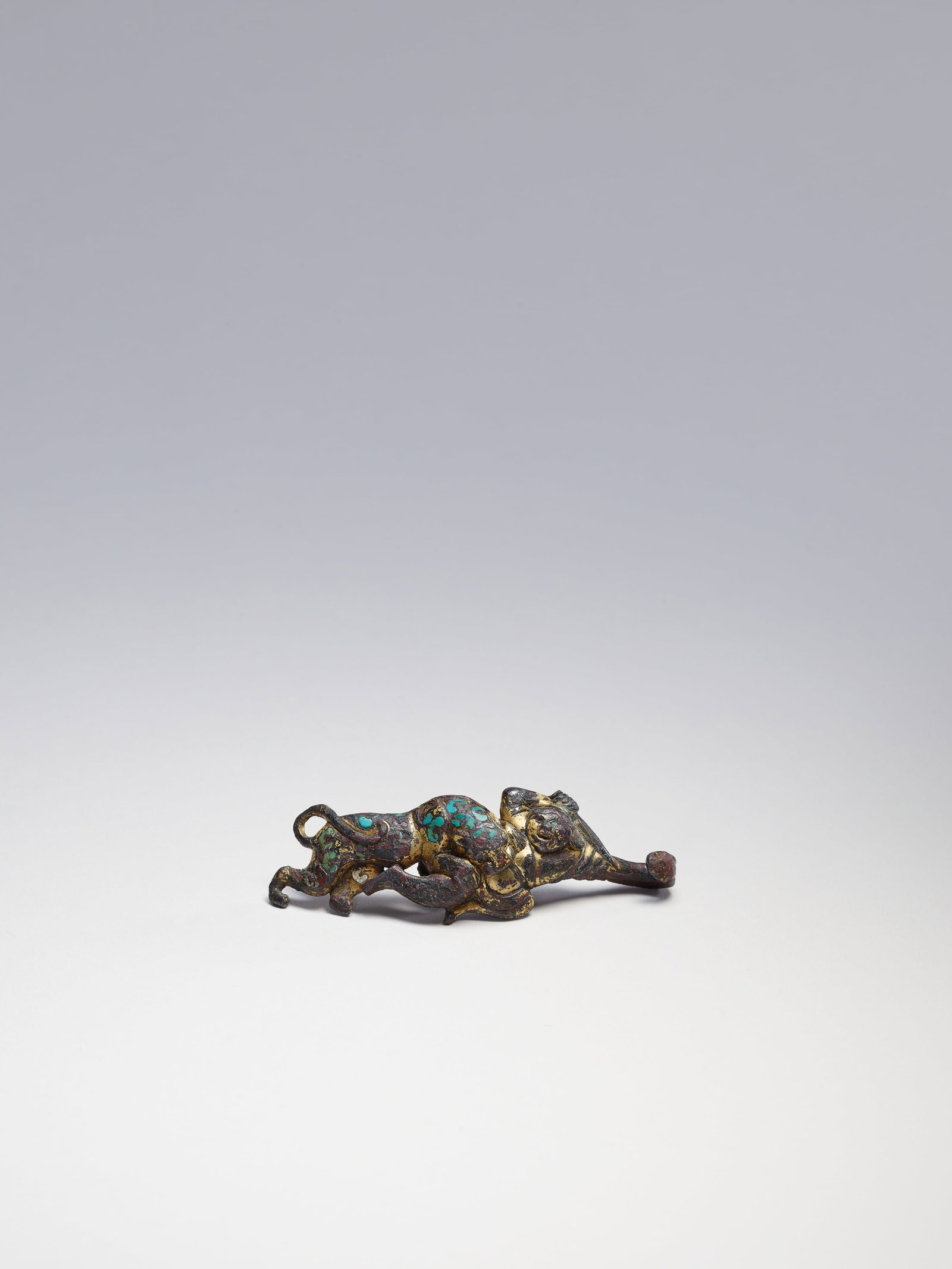 A RARE TURQUOISE-INLAID GILT-BRONZE 'WARRIOR AND LEOPARD' BELT HOOK: 年代(Age):WARRING STATES PERIOD OR HAN 。尺寸(Size):8.1 cm Length。 參閱：公元前3至1世紀 鎏金î