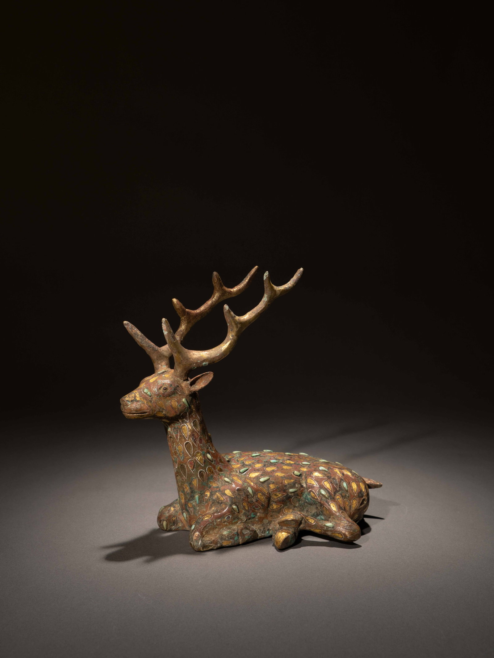 A GOLD, SILVER, AND TURQUOISE-INLAID BRONZE FIGURE OF A DEER: 年代(Age):HAN(206 B.C.-220 A.D.) 。尺寸(Size):18.3 cm Length, 18.1 cm Height。