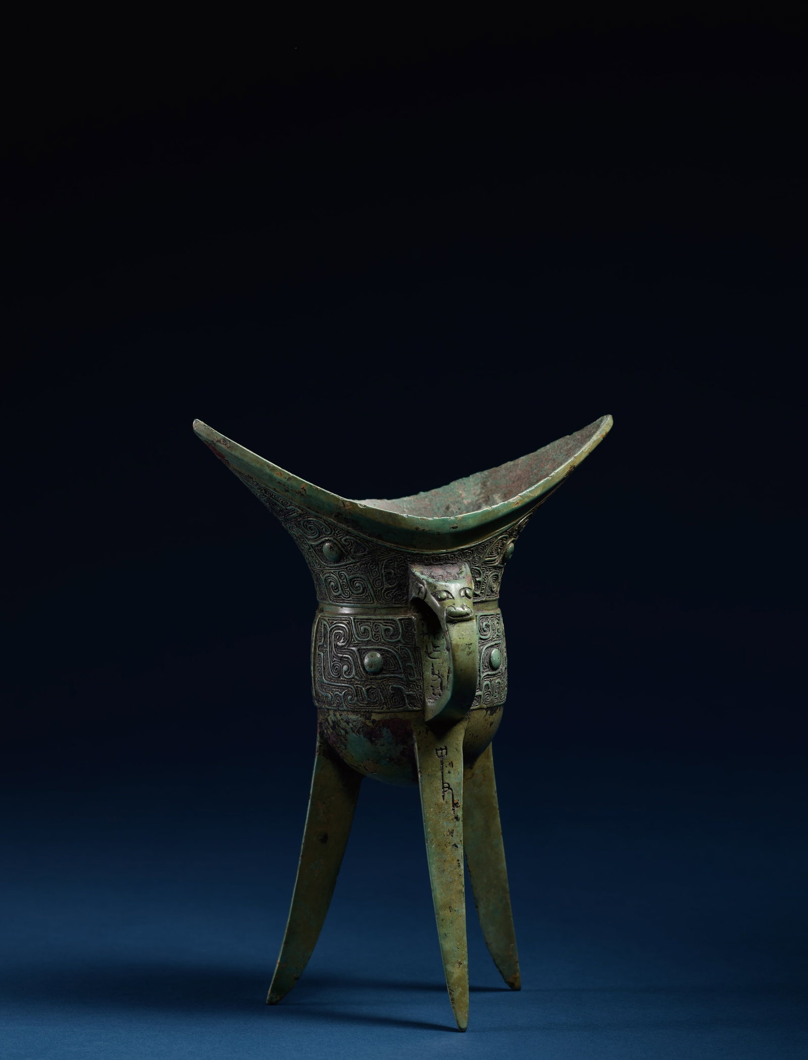 A VERY RARE AND IMPORTANT BRONZE RITUAL WINE VESSEL, JIAO: 年代(Age):LATE SHANG TO EARLY WESTERN ZHOU 尺寸:(Size):22.3 cm Height。拍品描述:口部弧曲，兩翼上&#