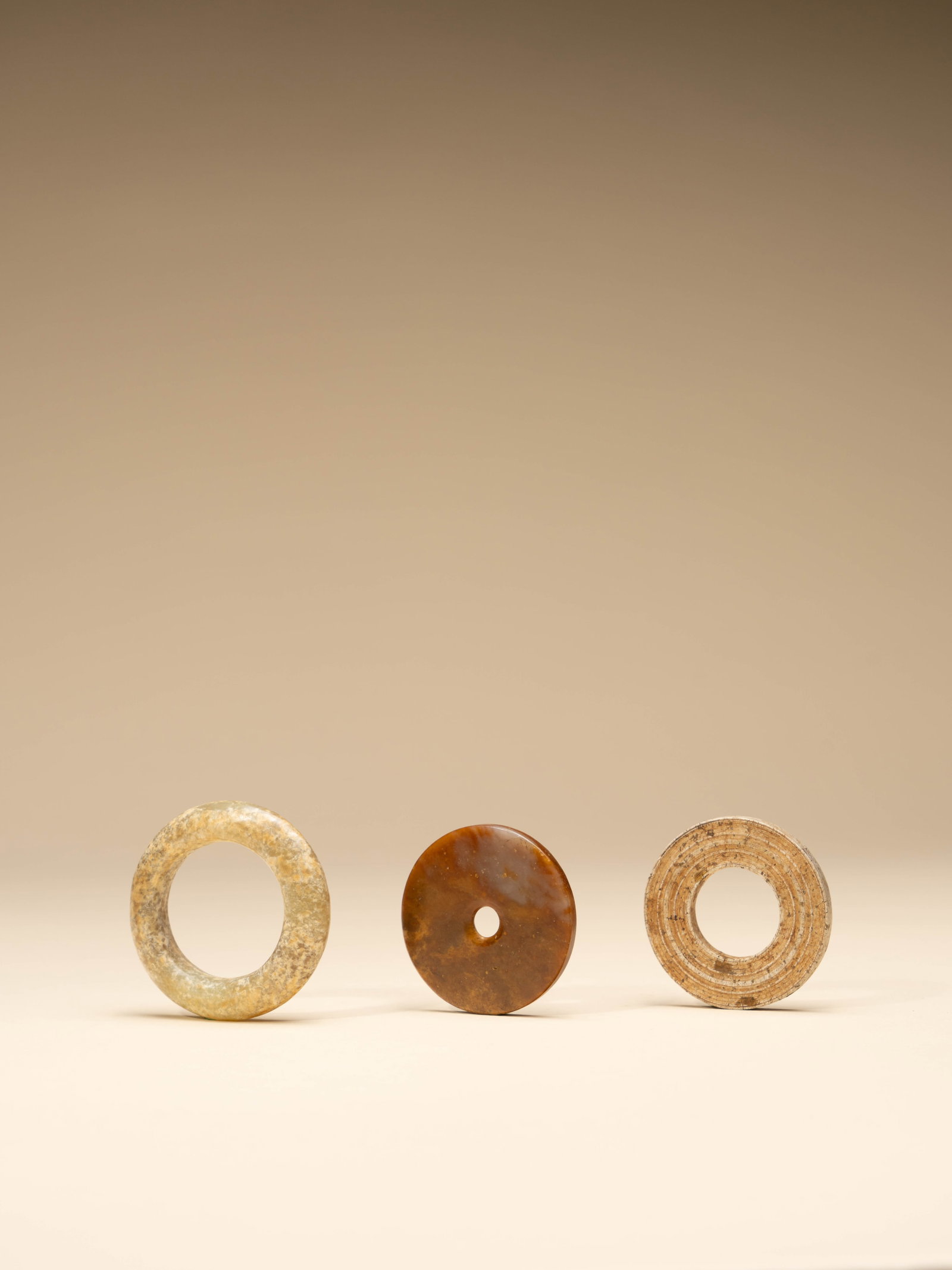 A GROUP OF JADES: 年代(Age):NEOLITHIC PERIOD 。尺寸(Size):5.6 cm Diameter / 5 cm Diameter / 5 cm Diameter。