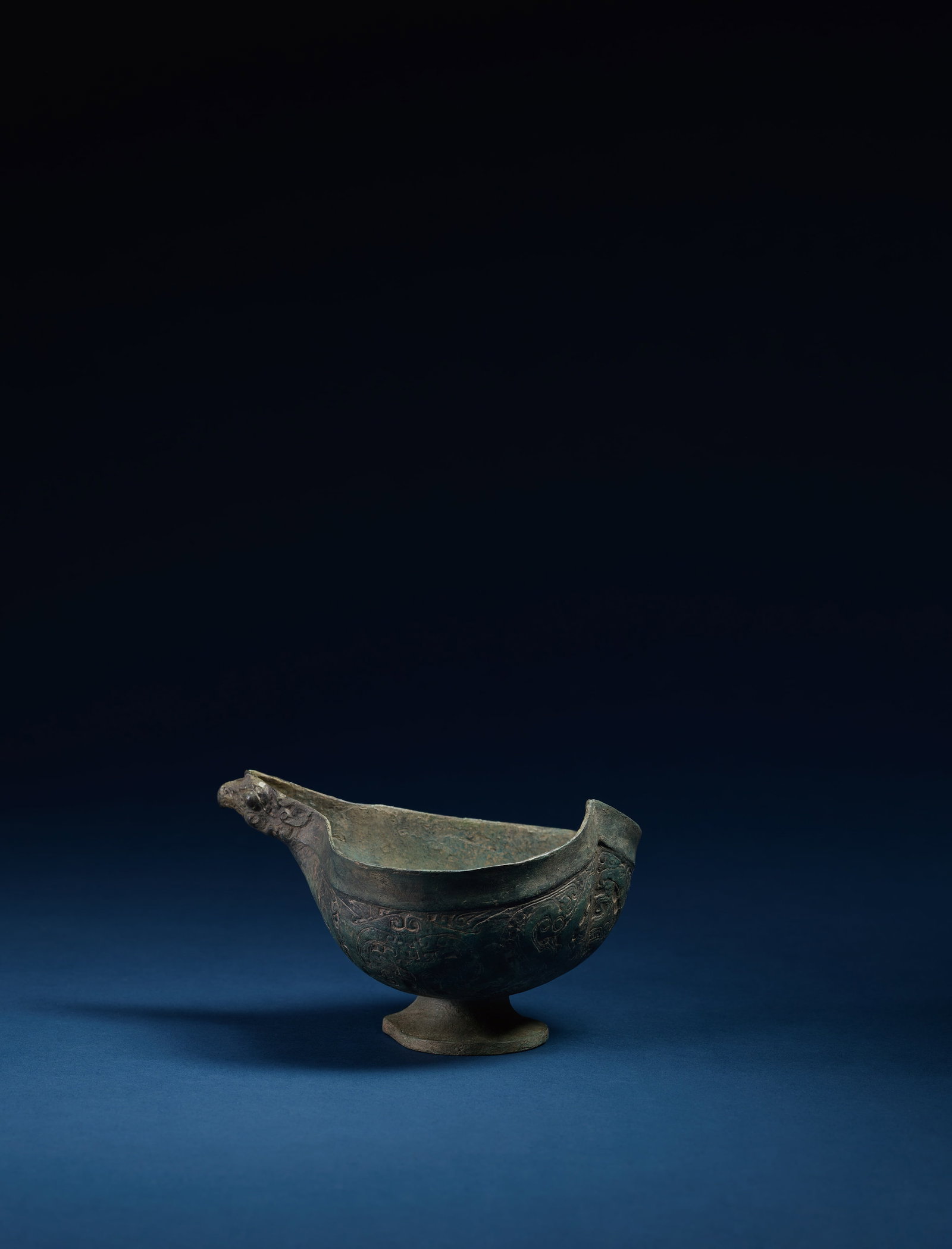 A BRONZE EAGLE-HEAD CUP: 年代(Age):WARRING STATES PERIOD(475-221 B.C.) 。尺寸(Size):15.5 cm Length, 9.3 cm Height。 拍品描述:敞口，深腹